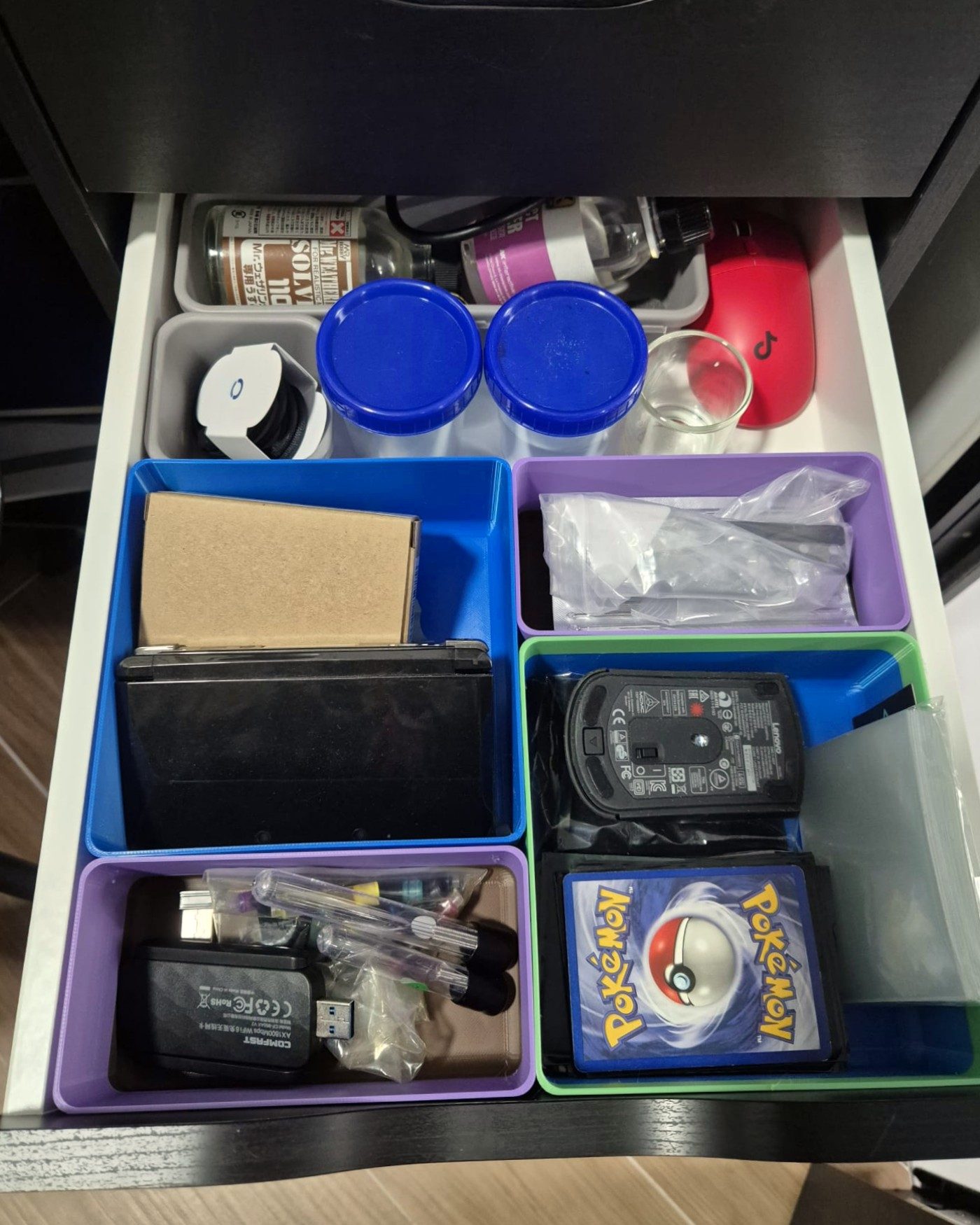 Drawer organised with blue, purple, and grey 3D-printed bins holding cards, a mouse, and electronics